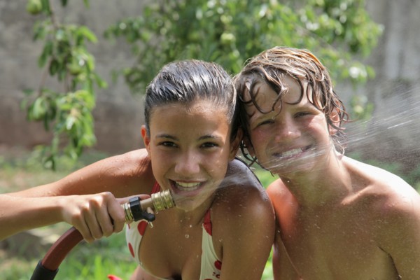 Boy (10-11) playing with water hose in summer. Photo: pauline st.denis