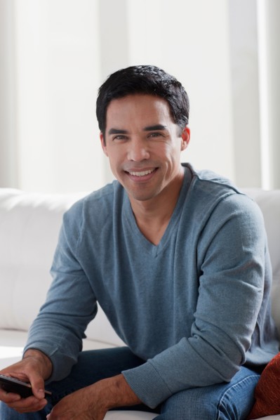 Portrait of smiling mid adult man sitting on sofa. Photo : Dan Bannister