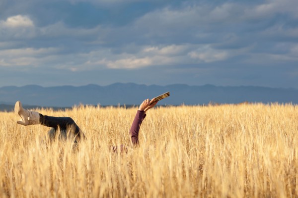 Woman lying in field holding digital tablet. Photo: Noah Clayton
