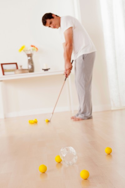 Man dressed in pajamas playing mini golf at home. Photo : Rob Lewine