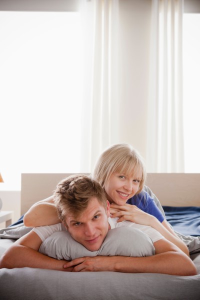 Woman lying atop man in bed. Photo: Rob Lewine