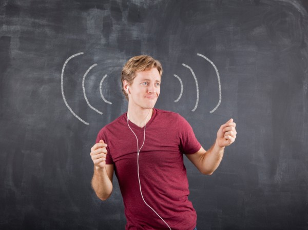 Studio shot of mid adult man listening to music on earphones and dancing with chalk drawing on