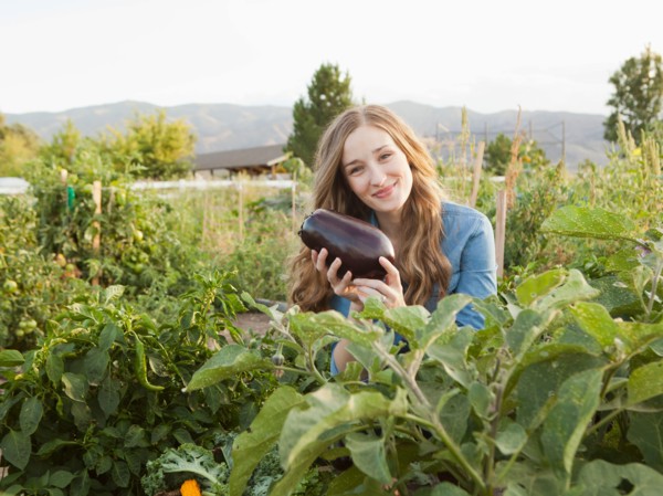 Portrait of young woman harvesting eggplant. Photo : Jessica Peterson