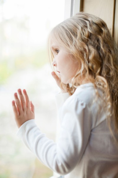 Girl (4-5) looking through window. Photo : Jessica Peterson