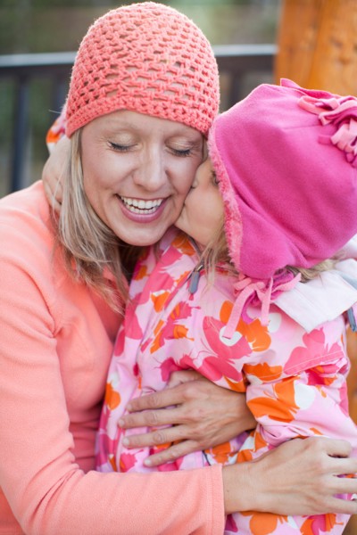 Daughter (4-5) kissing mother outdoors. Photo : Jessica Peterson