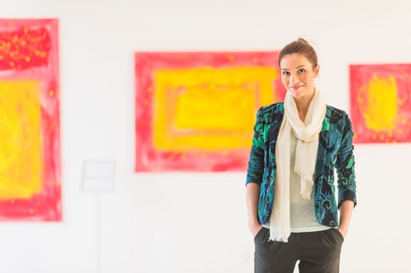 Portrait of woman with paintings in museum.