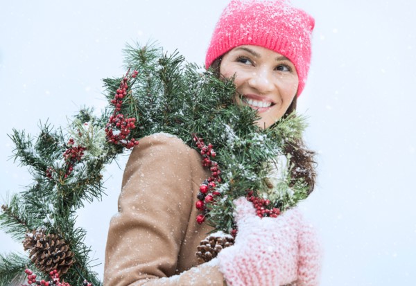Portrait of woman in winter clothes carrying wreath.