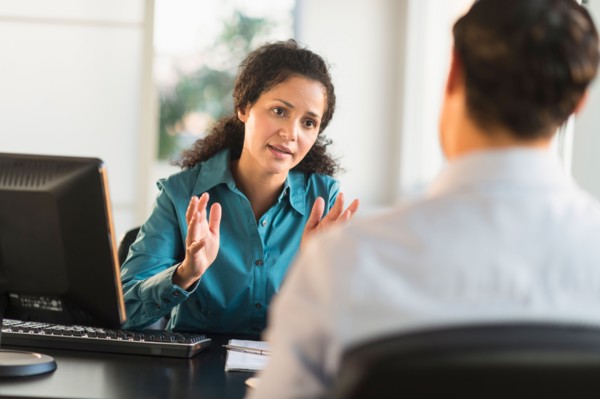 Woman interviewing man at desk.