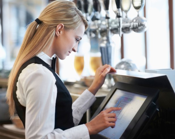 Young waitress using computer at restaurant counter