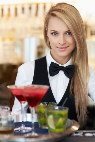 Portrait of female bartender holding tray with cocktails