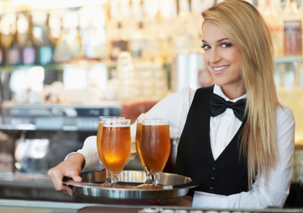 Portrait of young woman holding tray with beer glasses