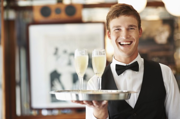 Portrait of waiter holding champagne flutes on tray