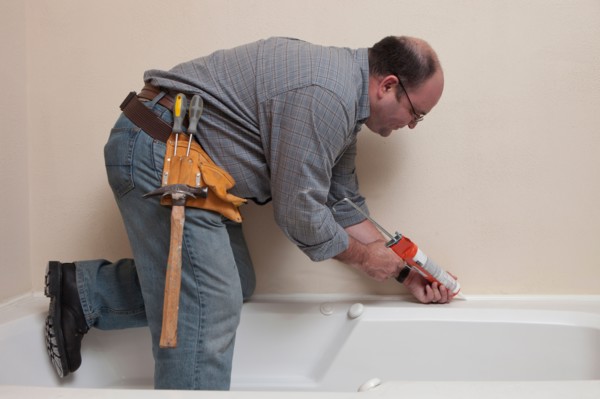 Man with Caulk Gun working in bathroom