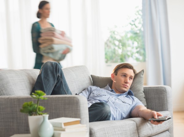 Man lying on sofa watching tv.