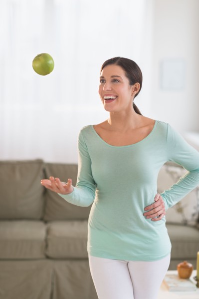 Woman juggling with apple at home.