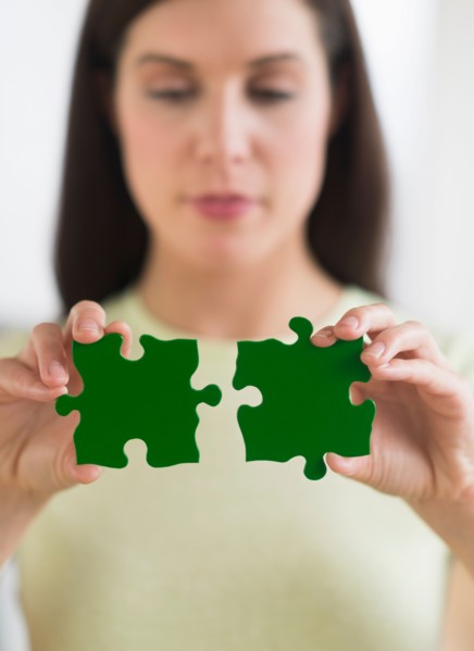 Woman holding green puzzle pieces.