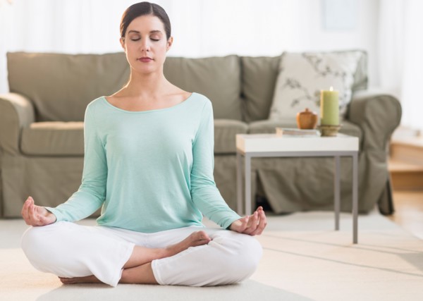 Woman meditating in living room.