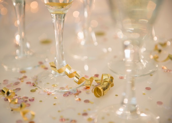 Champagne flutes on table decorated with confetti and streamer