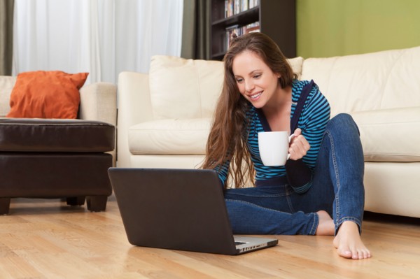 Smiling woman in living room using laptop