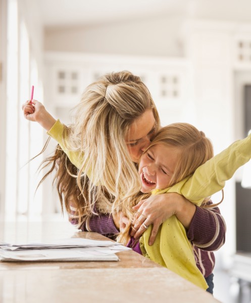 Mother kissing daughter (6-7) during doing homework