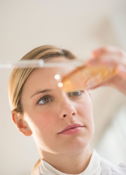 Close-up of scientist using pipette and petri dish.