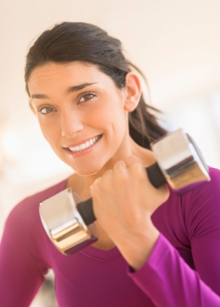 Young woman lifting dumbbell.