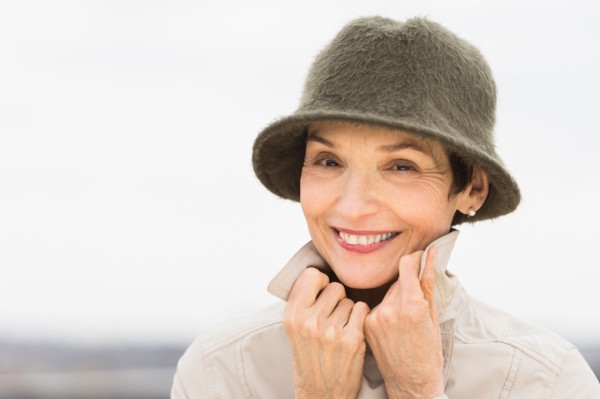 Portrait of smiling woman wearing raincoat and hat.