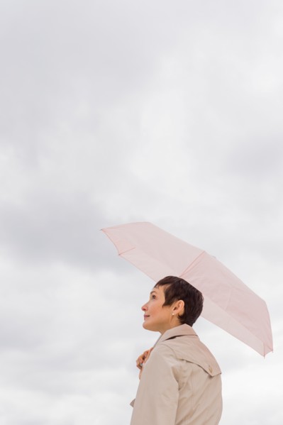 Woman wearing raincoat and holding umbrella.