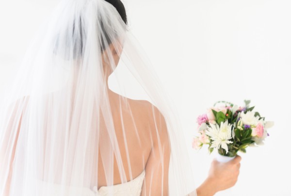 Portrait of bride in veil holding bouquet.