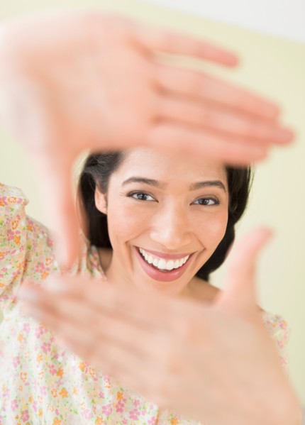 Young woman looking through hand frame.