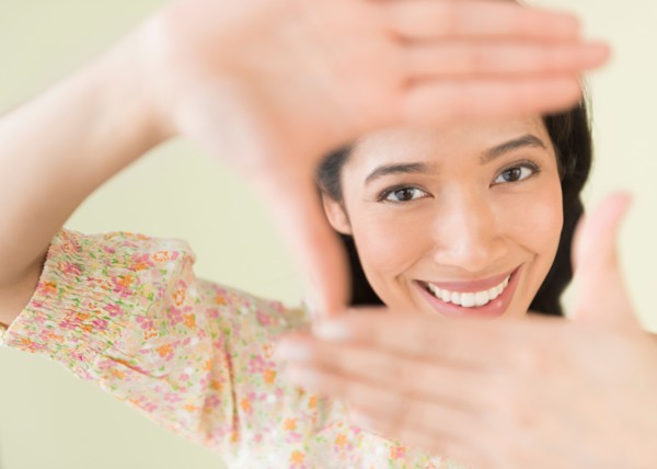Young woman looking through hand frame.