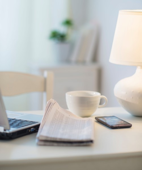 View of newspaper, laptop, mobile phone and cup