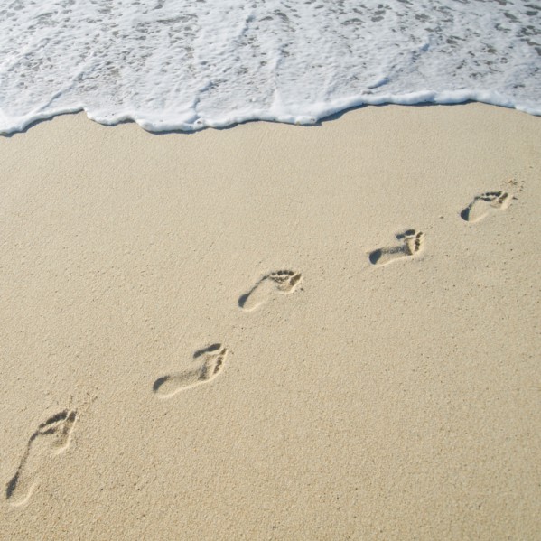 Footprints on Sandy Beach leading into sea