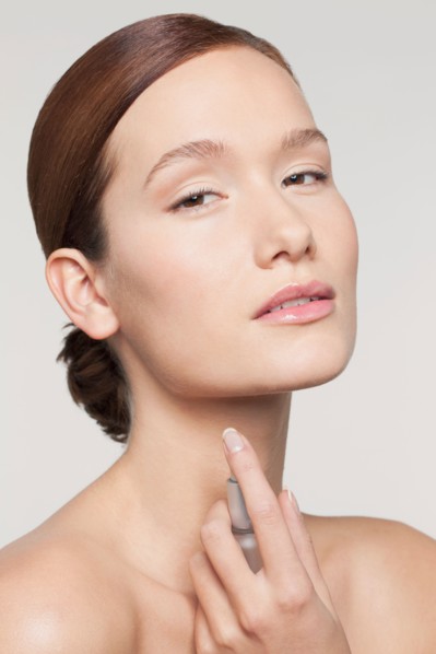 Studio shot portrait of young woman holding perfume