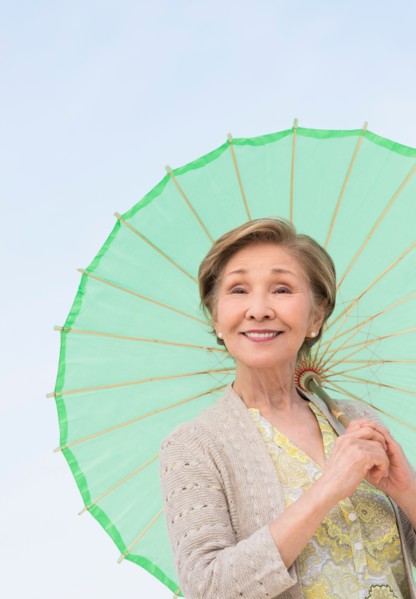 Portrait of senior woman holding green parasol.