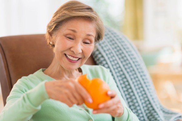 Portrait of senior woman peeling orange.