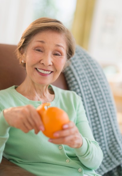 Portrait of senior woman peeling orange.