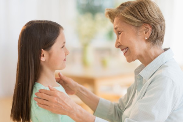 Granddaughter (8-9) and grandmother smiling to each other.