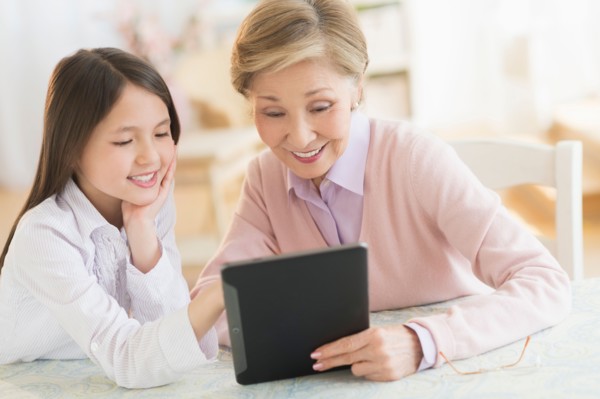Granddaughter (8-9) and grandmother using digital tablet.