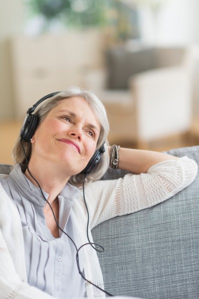 Senior woman sitting on sofa and listening to music.