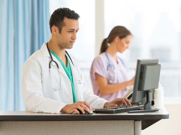 Male and female nurses working at nurse's station in hospital.