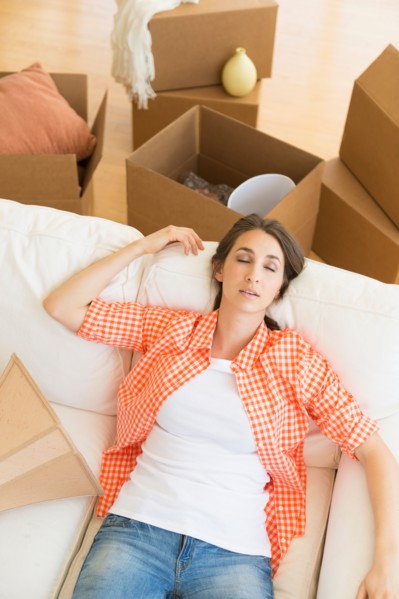 Young woman resting on sofa after moving into new home.