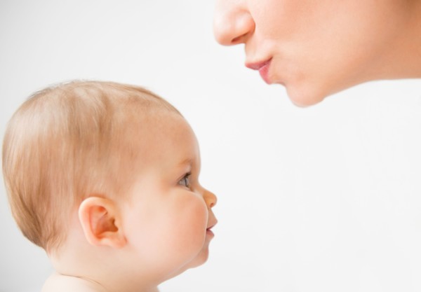 Side view of mother about to kiss her baby daughter (6-11 months)