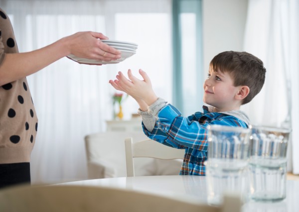 Boy (4-5) helping mother to set table