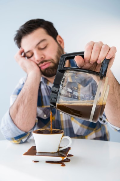 Tired, sleepy man spilling coffee on table