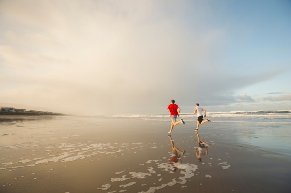 Young adult men running on beach