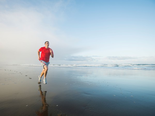 Young adult man running on beach