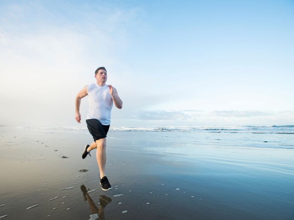Young adult man running on beach