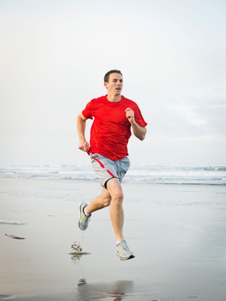 Young adult man running on beach