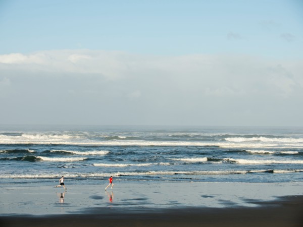 Young adult men running on beach